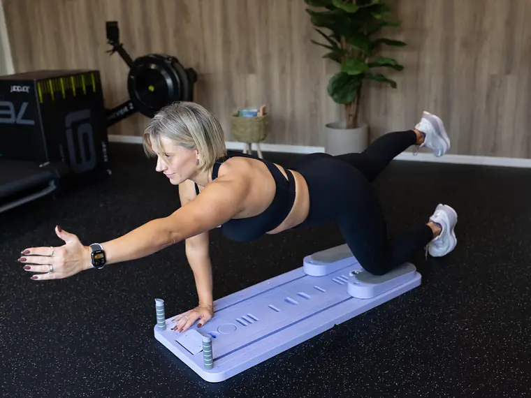 Woman training on the Neart Pilates reformer board in a home gym